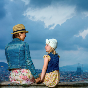 从后面看到的时髦的母亲和儿童游客对巴塞罗那城市全景