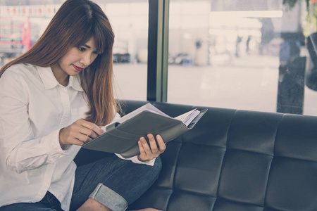 女人坐在沙发上的咖啡馆。女学生在笔记本中读笔记