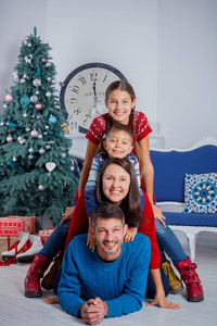 父母和两个可爱的孩子在圣诞树附近玩得很开心