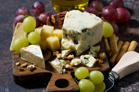 cheeseboard，新鲜水果和蜂蜜上黑色的桌子，特写