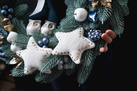 女性手持美丽的圣诞花环与黑色背景的白色星星的特写