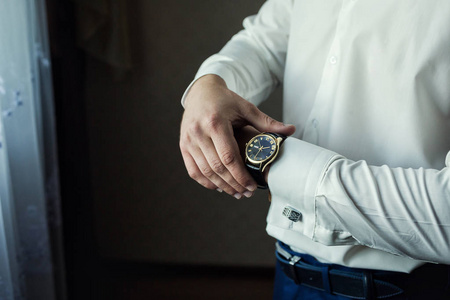 商人在他的腕表上检查时间, 男子把时钟放在手上, 新郎在婚礼前的早上准备