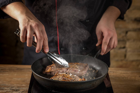 男性手的特写在热平底锅准备肉与香料