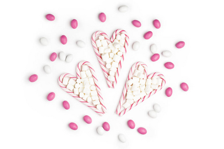 粉红色和白色的糖果和棒糖的形式心顶视图白色背景情人节