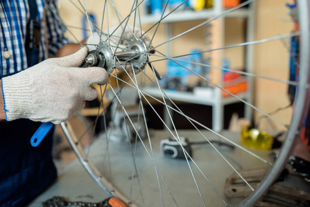 在修理自行车车轮时, 不识别的修理工戴着工作手套的特写镜头, 背景模糊