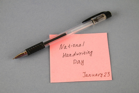 带铭文的便条是全国的手写日和灰色背景的钢笔