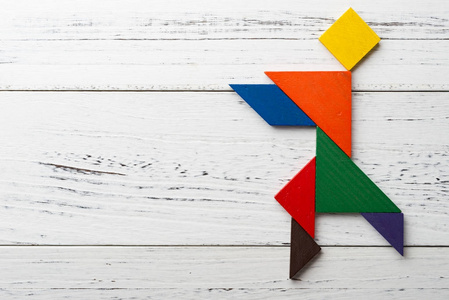 木七巧板在跳舞的人形状与复制空间照片