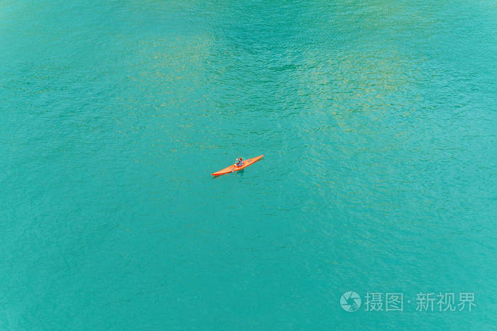 人在红色独木舟在蓝色海上部看法的中间