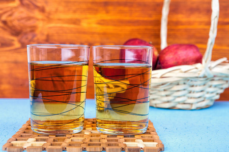 木制背景下的两杯苹果汁和红苹果