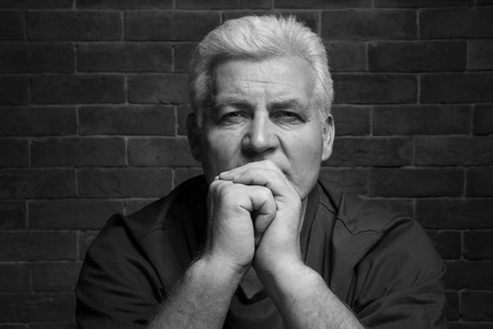 英俊的老人在休闲的衣裳在砖墙壁背景, 黑白作用照片