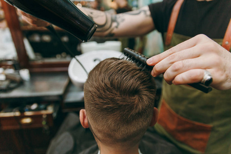 近距离拍摄的人在理发店流行发型。男性发型师在纹身服务客户, 干燥头发与吹风机
