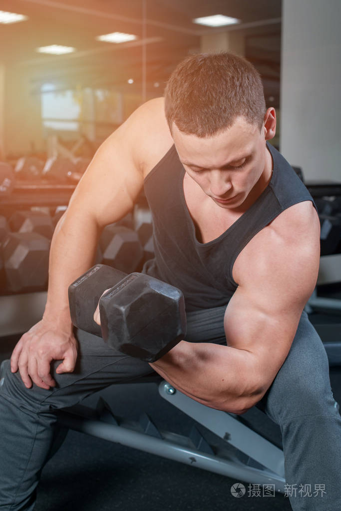 体育概念健美运动员在健身房用哑铃锻炼