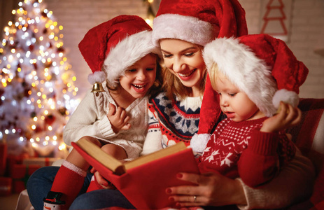 家庭的母亲和孩子们读了一本书在圣诞节附近 firep