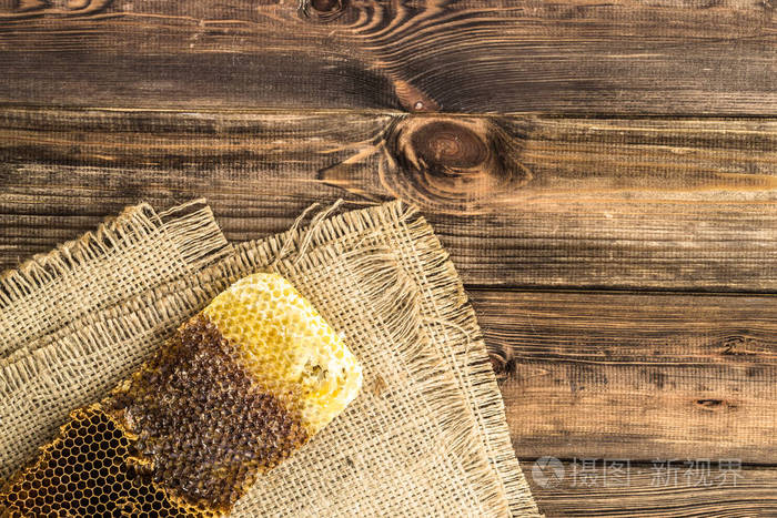蜂窝与蜂蜜在质朴的木材背景覆盖黄麻麻布顶部视图