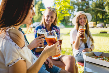 快乐的白种女孩在公园野餐。微笑和谈话, enjoing 比萨与啤酒