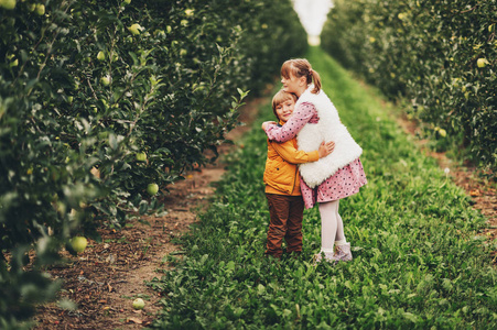 两个有趣的孩子们玩在绿色的苹果园，快乐的童年，在农村