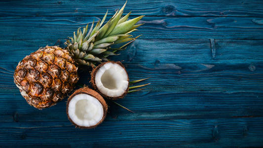 椰子和菠萝的木制背景。热带水果和坚果。顶部视图。文本的可用空间