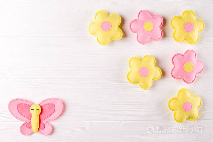 工艺粉红色和黄色蝴蝶和花朵，白色木制背景上的 copyspace。手工毛毡的玩具。抽象的天空