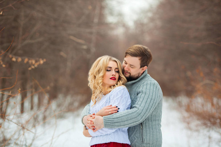 美丽的年轻情侣相爱, 穿浅色毛衣, 在寒冷的天气里漫步在公园里