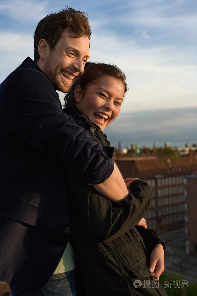 年轻迷人的多民族情侣拥抱城市背景
