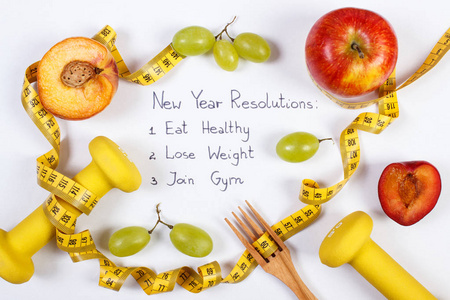 新年决心或目标果子哑铃和卷尺健康食物和生活方式概念