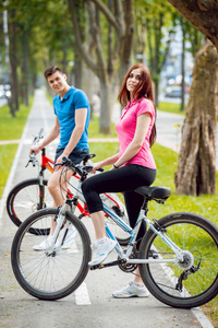 公园里骑自行车的年轻人和女孩。美丽的自行车车道
