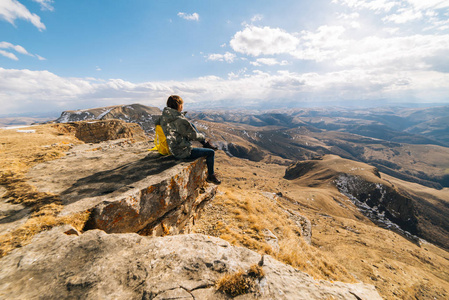一个运动的年轻女孩坐在悬崖边上, 享受自然和山脉