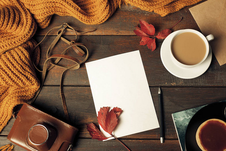 打开的工艺纸信封，秋天的落叶和木制的桌子上的咖啡