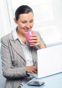带着微笑的年轻商务女性，带着笔记本电脑的杯子