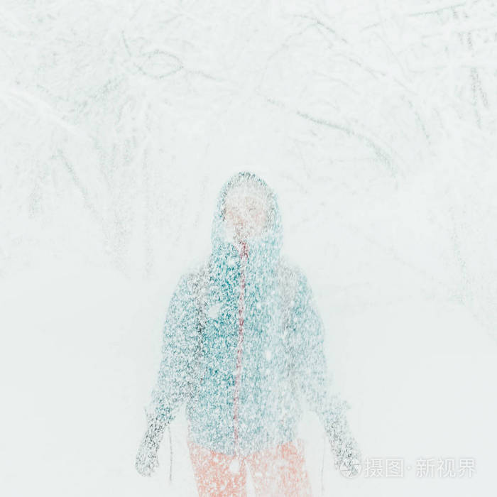 妇女站立在下落的雪之下