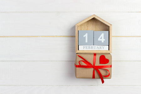 立方体日历与红色心脏和礼物箱子在木桌与拷贝空间。2月14日概念