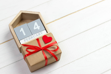 2月14日。在情人节贺卡上的红心和礼品盒的木日历。复制空间