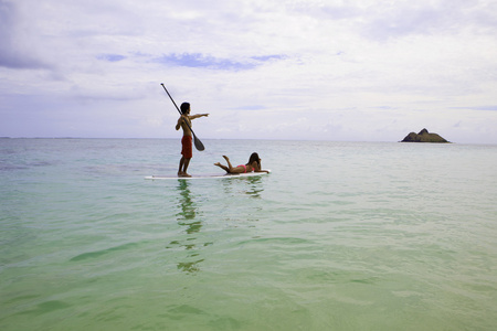 沙滩男孩和比基尼女郎在桨板上