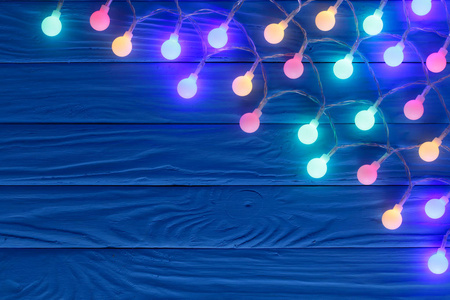 圣诞花环灯在蓝色木背景与复制空间为您的文本。顶部视图