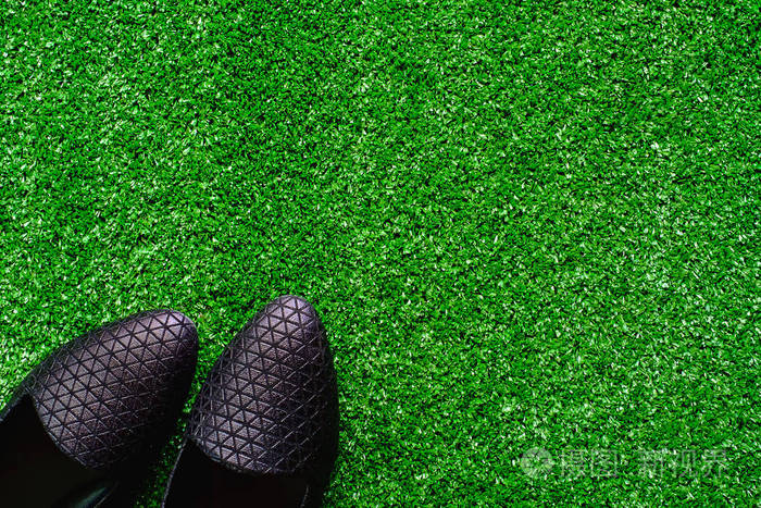 在塑料人工绿色草地上的黑鞋
