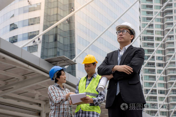 一位身穿安全帽建筑师的亚洲严肃工程师在后台讨论施工方案照片-正版