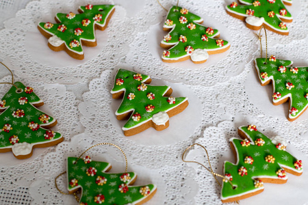 在白色餐巾背景下, 在圣诞树的形状上涂上姜饼。圣诞树曲奇饼五颜六色的结冰装饰