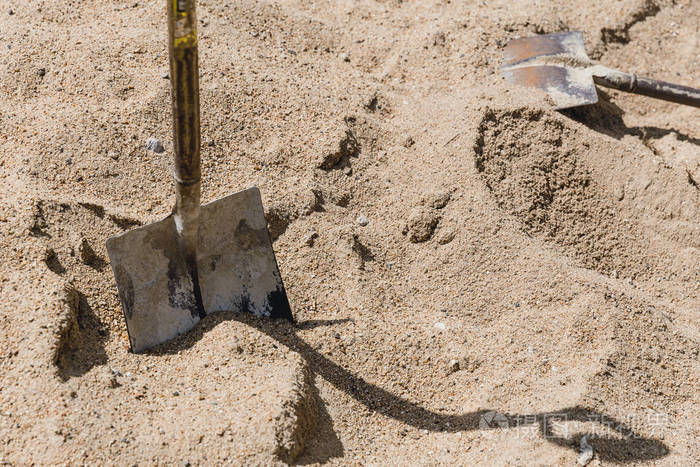 在阳光明媚的日子里, 把铲子放在沙子上施工