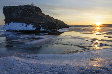 冰和水附近的山上的冰冻贝加尔湖。日落