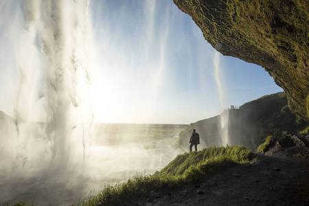 游客站在 Seljalandsfoss 在冰岛南部，Seljalandsfoss，冰岛最著名的瀑布之一