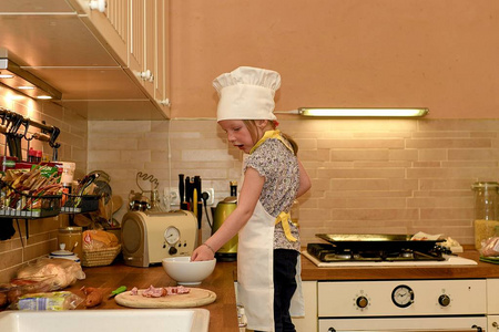 可爱的小女孩在乡下的厨房里做饭。小女孩准备比萨饼