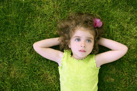 漂亮的小宝宝女孩快乐躺在草地上
