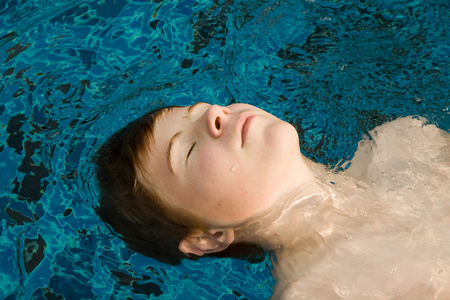 池中的男孩在游泳池中的红头发的男孩照片