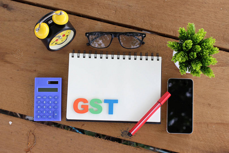 用计算器和笔记本在木桌上的 Gst 概念