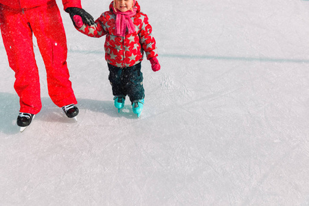 父亲和小女儿学习在冬天滑冰