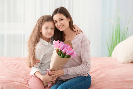年轻女子和她的女儿在室内郁金香花束。母亲节庆典