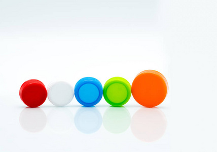不同大小的白色, 绿色, 红色, 蓝色和橙色的圆形塑料螺丝帽在白色的背景和复制空间线