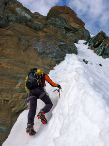 在一个陡峭的北面上的雄性登山者在 couloir 附近的瑞士阿尔卑斯山上上升