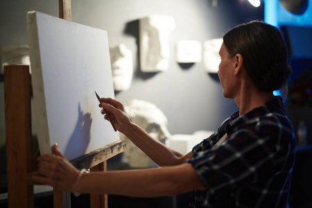 才华横溢的成熟女性画像艺术家画室空白白色画布上的石膏头模型