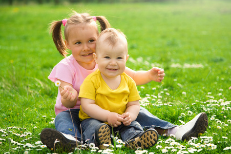 两个孩子坐在绿色的草地上